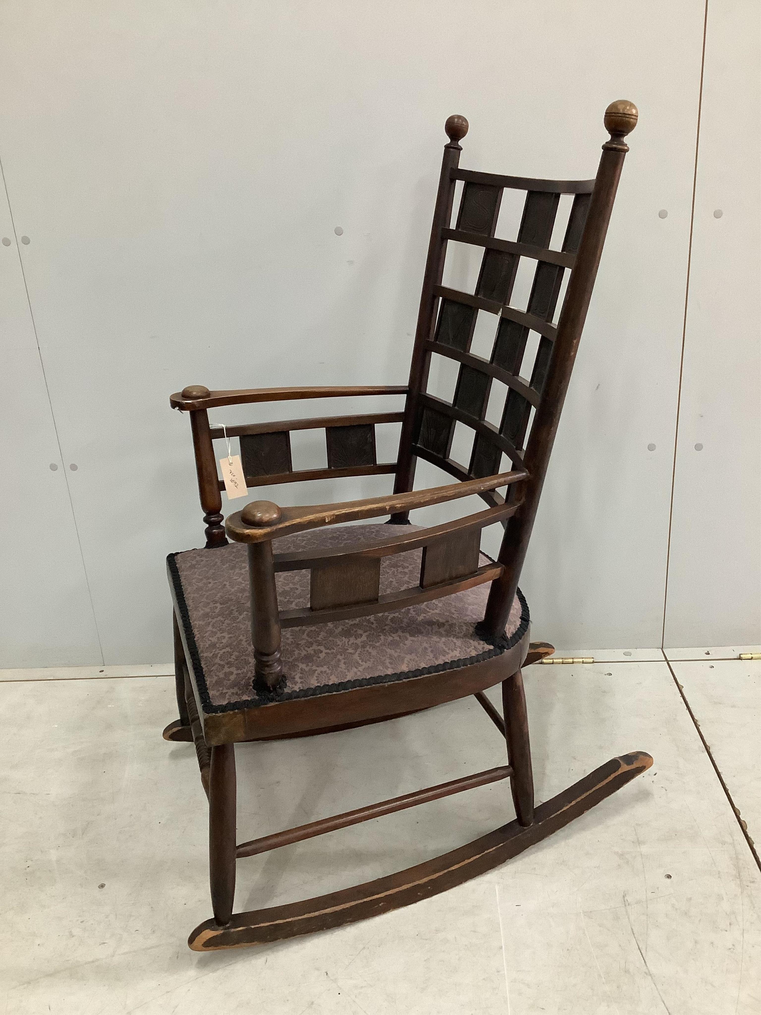 An Arts & Crafts mahogany rocking chair with copper panelled back inscribed 'Siste Viator' (stop, traveler - often used on Roman roadside tombs), width 60cm, depth 45cm, height 108cm. Condition - fair